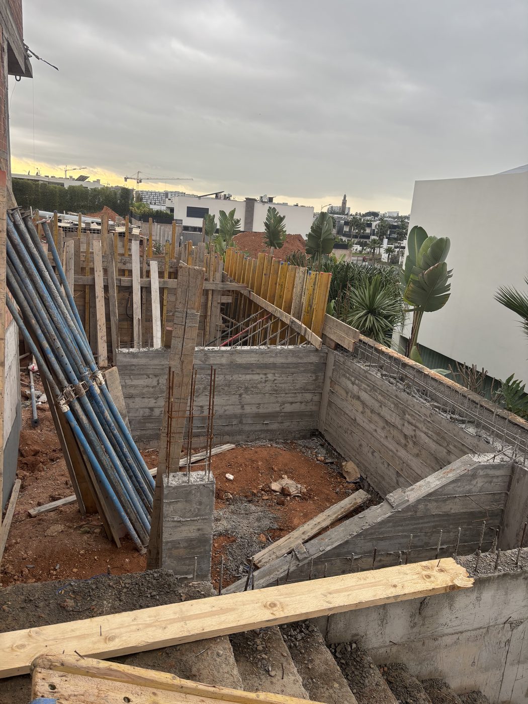 Murs de fondation en béton armé avec ferraillage vertical apparent et terre excavée autour