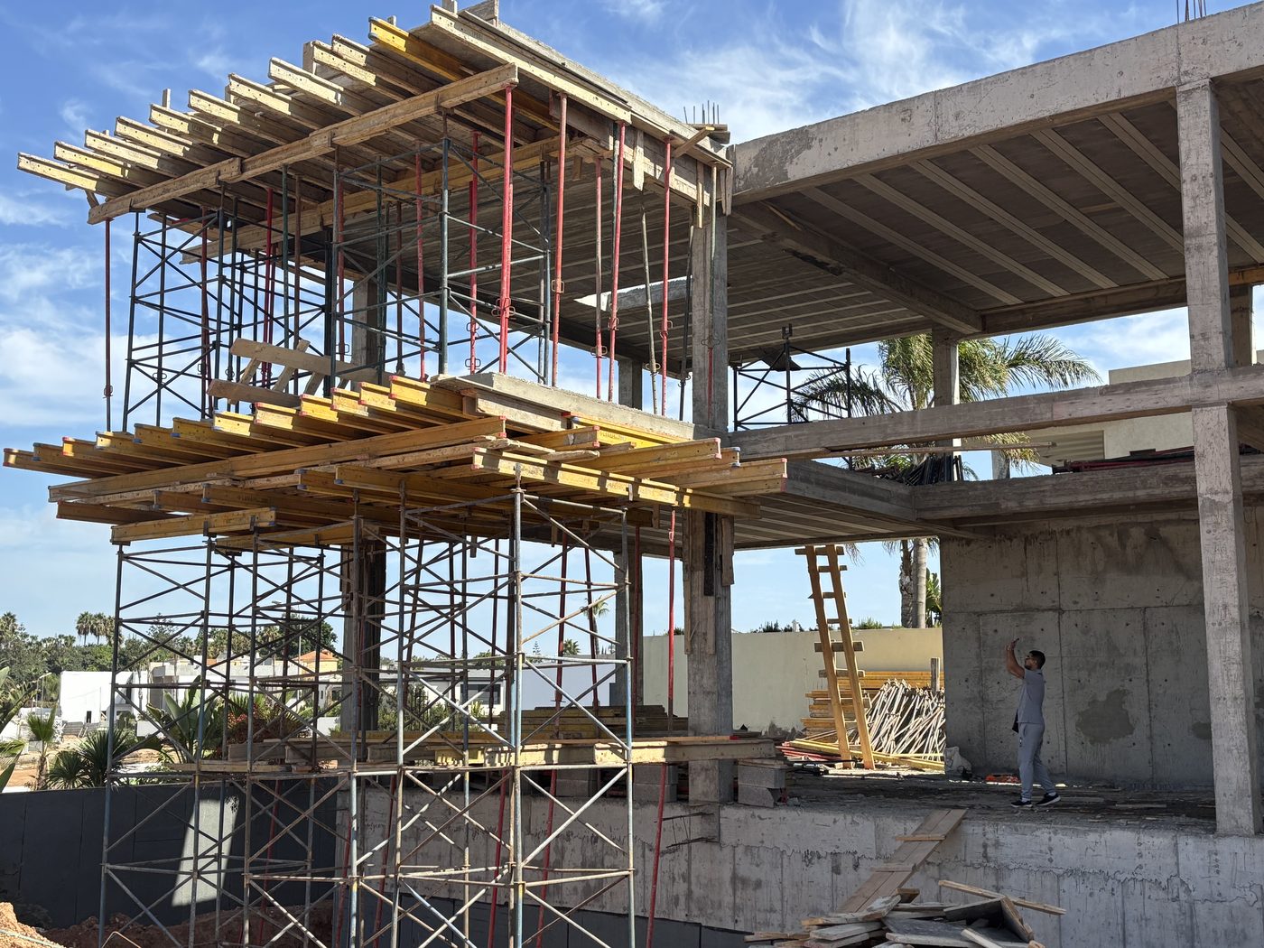Structure béton multi-niveaux avec ouvriers et échafaudages sur un immeuble en cours de construction