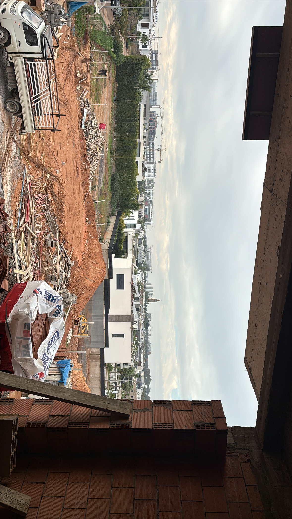 Vue d'ensemble d'un chantier avec matériaux empilés, terre excavée et constructions voisines